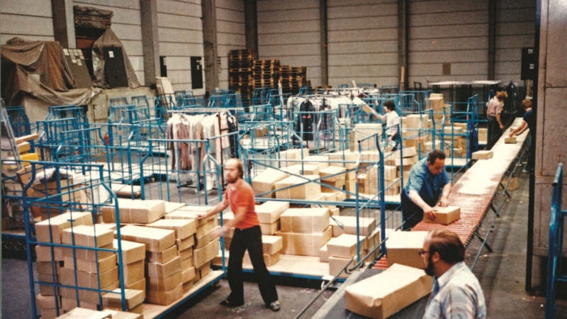 Mitarbeitende packen an und wickeln Pakete ab, in einem Hermes Lager in alten Zeiten (Foto: Hermes)