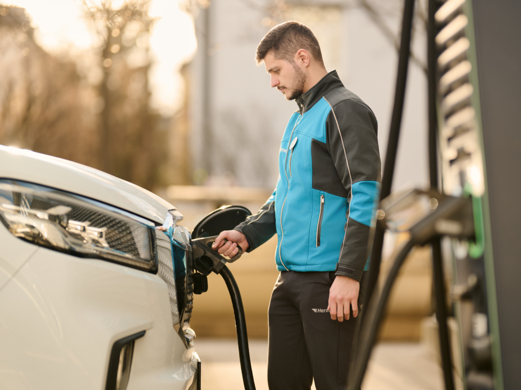 Hermes Zusteller mit seinem E-Fahrzeug an einer Ladesäule in München (Foto: Hermes Germany / Willing-Holtz)